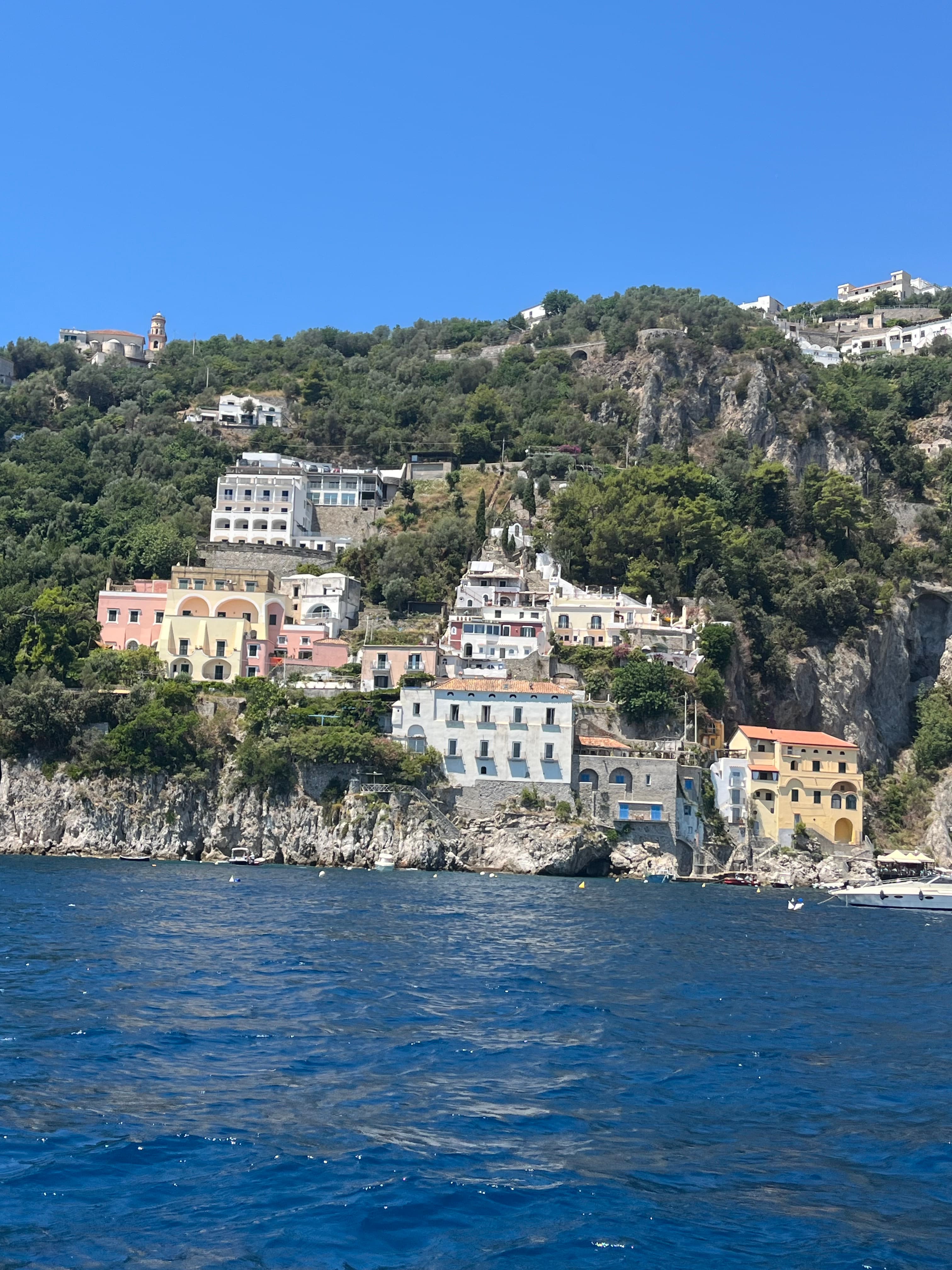 Colorful hillside buildings overlooking the sea under a bright blue sky.